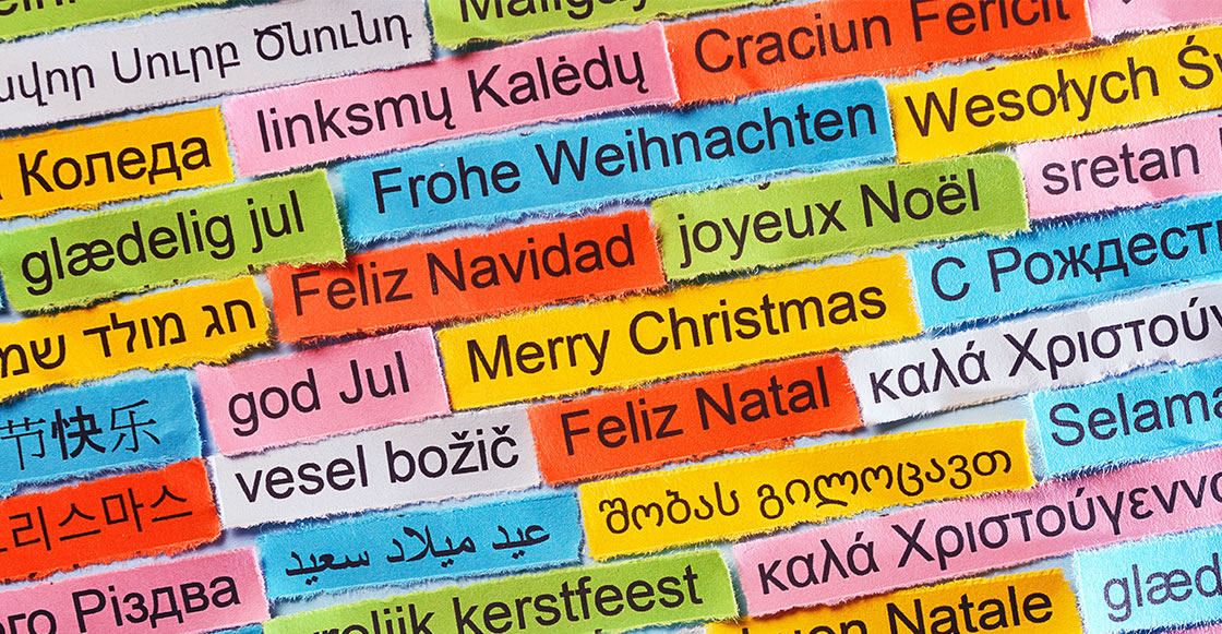 Bild mit vielen farbigen Karten mit der Aufschrift Frohe Weihnachten in verschiedenen europäischen Sprachen, für internationale Grüße